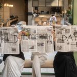 Three people holding newspapers promoting World Photography Day in a cozy Ankara café. — How 55 Club Protects Your Personal D
