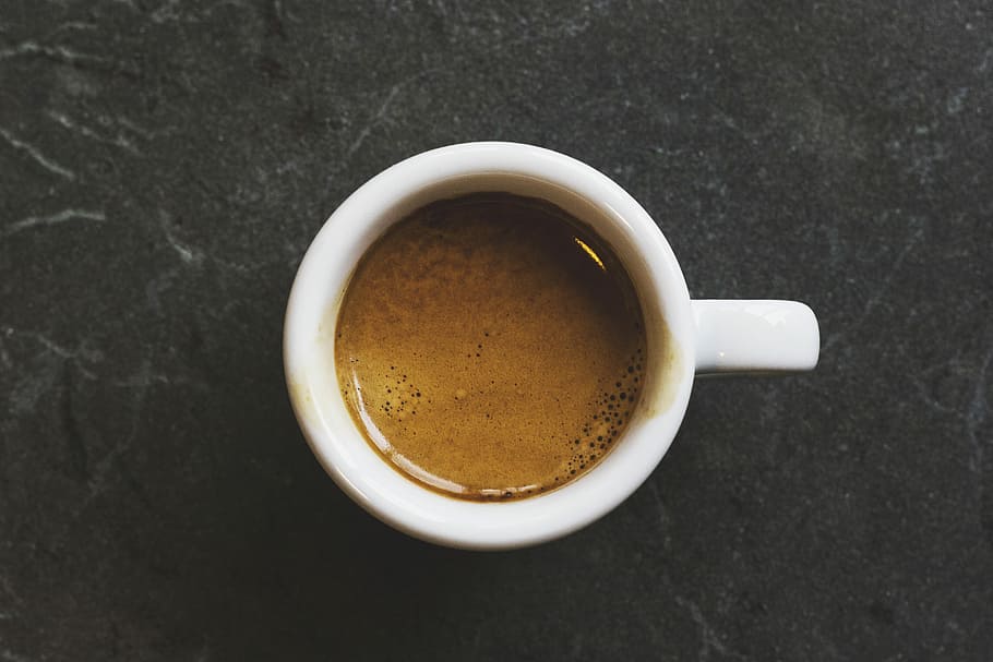 a top-down view of a small cup of espresso on a dark countertop